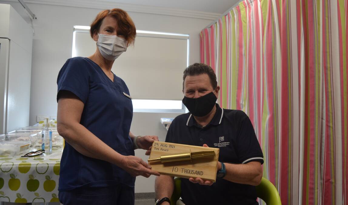 GOLDEN VAX: Tim Foley received a makeshift plaque from the Shoalhaven Family Medical Centre's to celebrate the milestone.