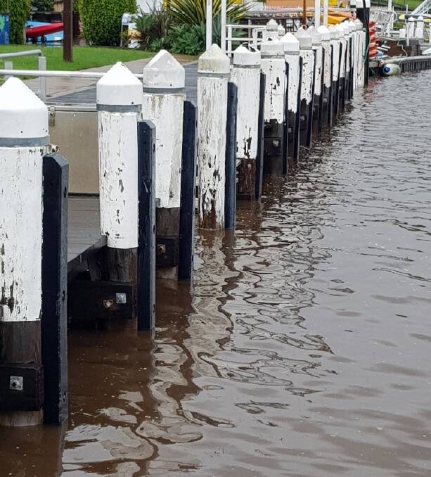 WATER RISING: High tide at Huskisson wharf Wednesday morning, water running brown with the soil. Image: supplied.