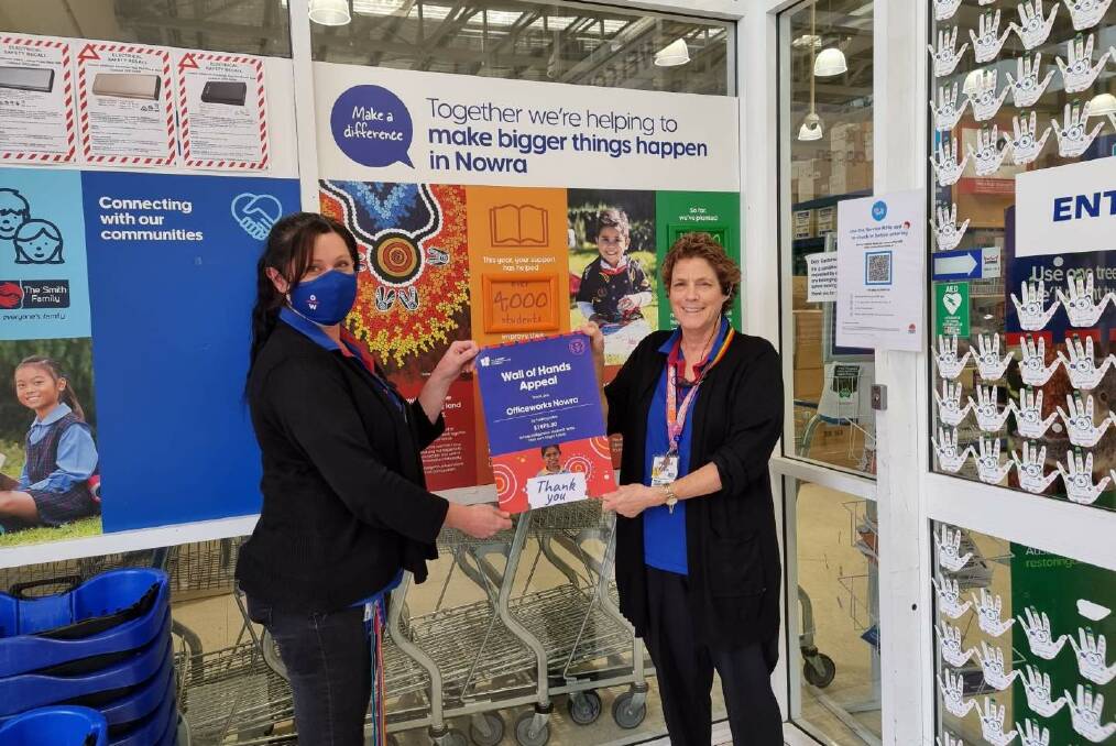LENDING A HAND: Officeworks Nowra team members Jo-Anne Fulton and Pam Ryan with the Wall of Hands Appeal. Image: supplied.