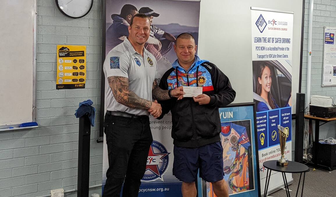 Ashton Sims (Left) presenting a cheque to Senior constable Nathan Ward (Right). Picture: Sam Baker 