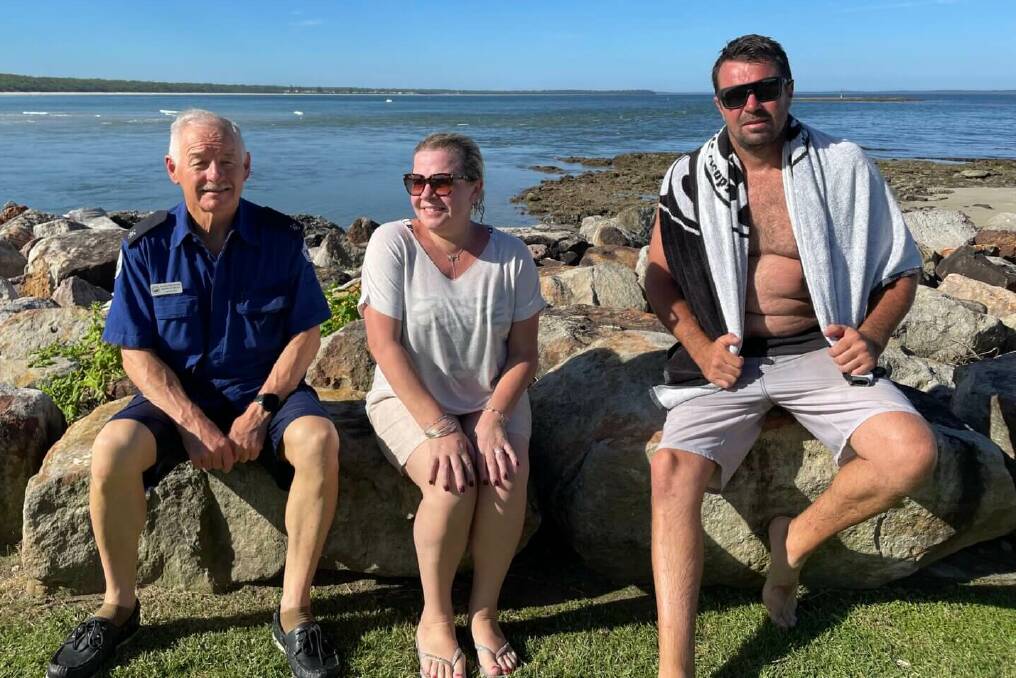 Nathan Parnell (right) uses a towel to dry off while sitting with Marine Rescue Jervis Bay volunteer Norm Stanley and British tourist Charlotte Breen following the rescue at Huskisson.