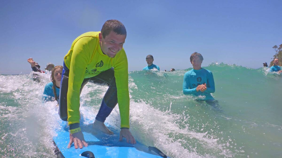 Scott Colebrook gets to his feet while riding a wave during the Disabled Surfers Association South Coast branch day at Mollymook. Picture supplied.