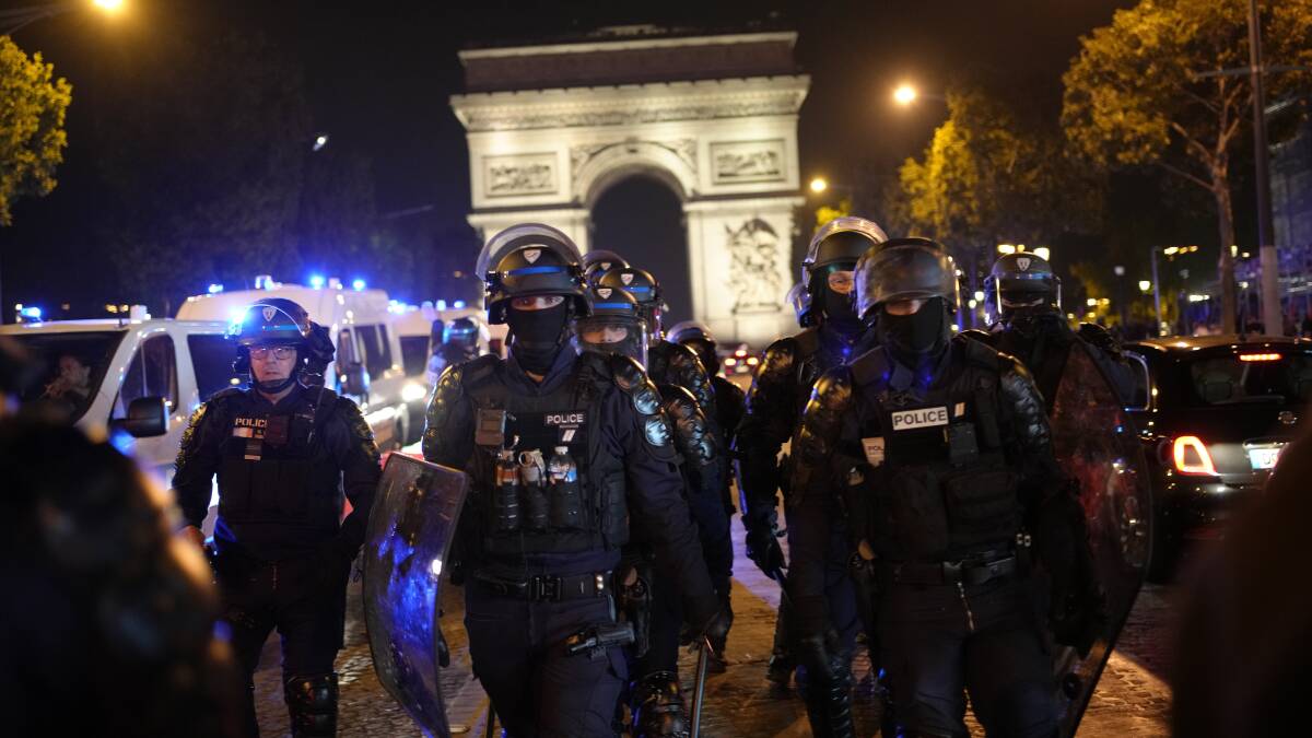 Police patrol in front of Paris landmark the Arc de Triomphe on July 1 during another night of rioting and looting in France. Picture by AP Photo/Christophe Ena
