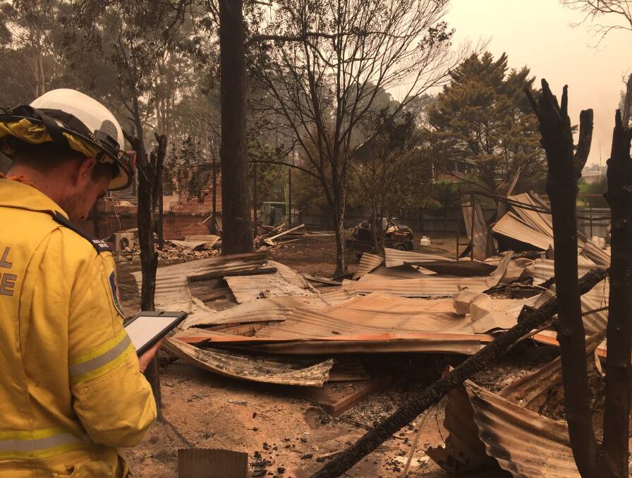 COUNTING THE COST: A Rural Fire Service assessor takes notes in Mogo on New Year's Day after fire swept through the day before. PICTURE: Kerrie O'Connor.