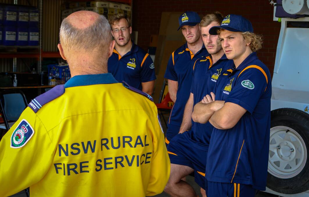 Will Miller (second from right) and his Brumbies teammtes listen to a member of the NSW Rural Fire Service. Photo: Brumbies Media