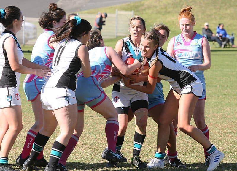 Kiama Power's Nellie Hicks (right with braids) tries to win possession for her team against the Wollongong Saints. Photo: AFLSC