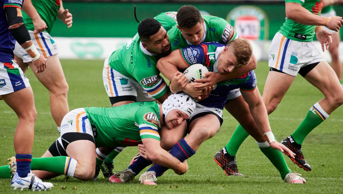 Warriors' Jack Murchie is tackled by his former Raiders teammates on Sunday. Photo: Matt Loxton