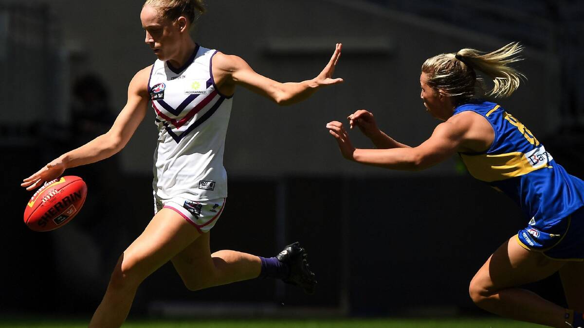 Dockers' Stephanie Cain gets a kick away despite pressure from Eagles' Maddy Collier. Photo: AFL Photos