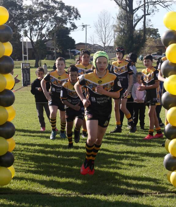 Under 13 Warrior Nate Stewart leads his team onto the field during his 100th game for the club.