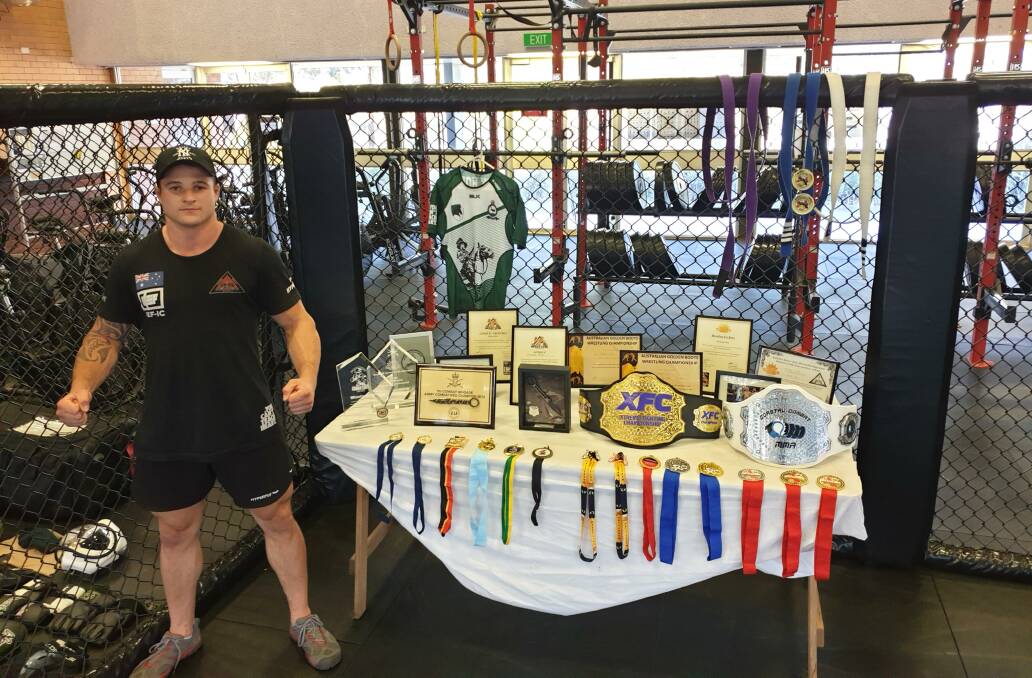 Michael Moss with his two belts and numerous trophies and medals. Photo: SUPPLIED
