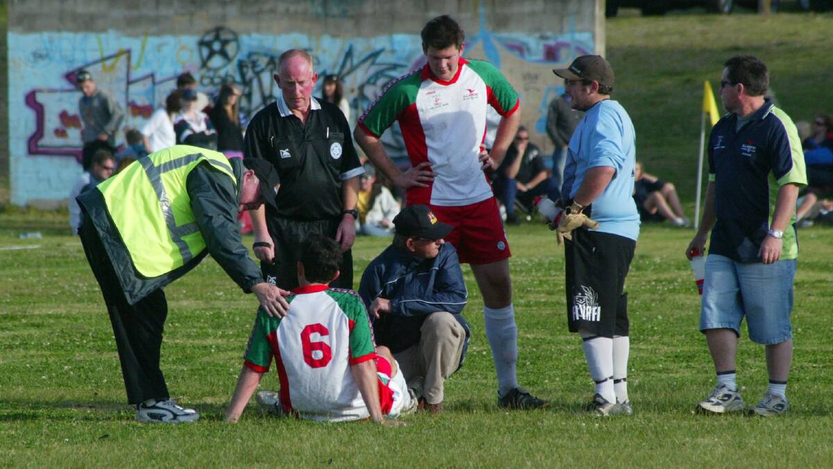 Sam Leedham's father Peter (centre) treats him after he broke his leg in the 2008 grand final. Photo: ROBERT CRAWFORD