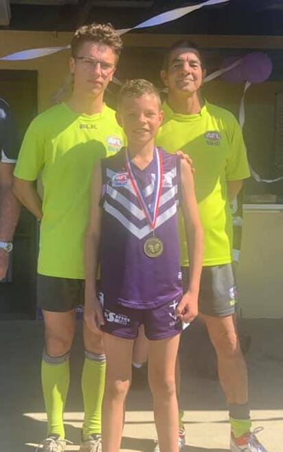 Dockers' Lachlan Barry with his Best on Ground award anf the two match officials.