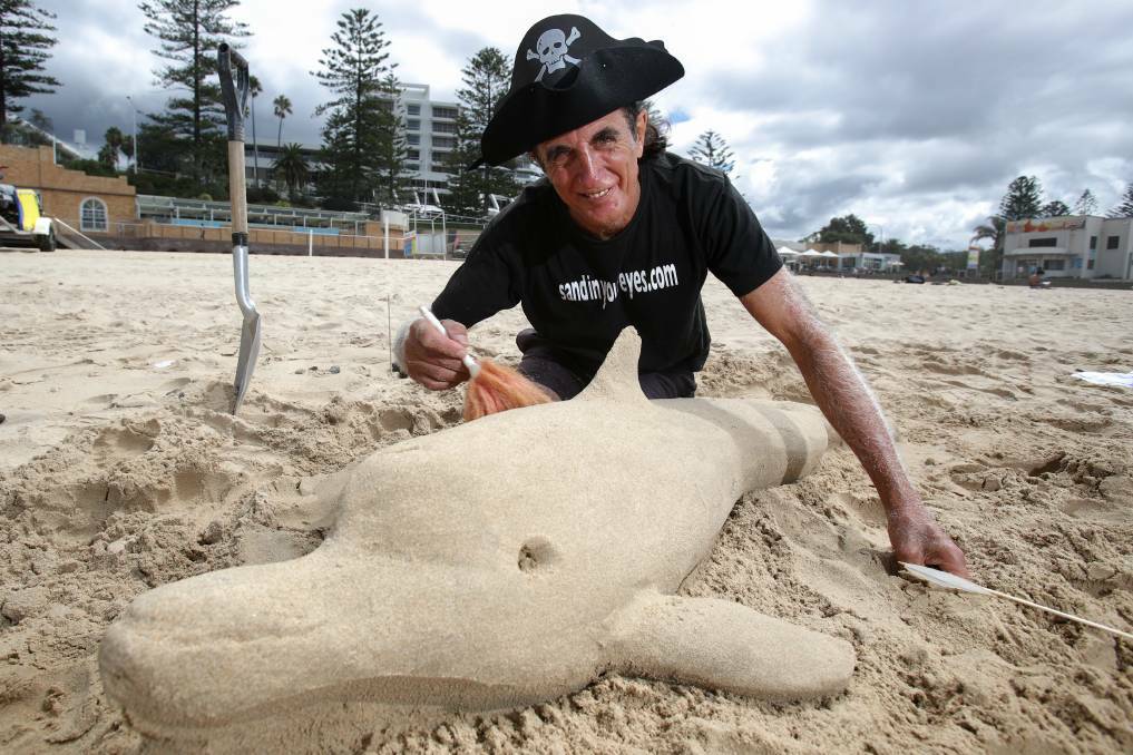 World champion sand sculptor Dennis Massoud with an unfinished dolphin he quickly created at a Wollongong beach earlier this year. Picture: Adam McLean.