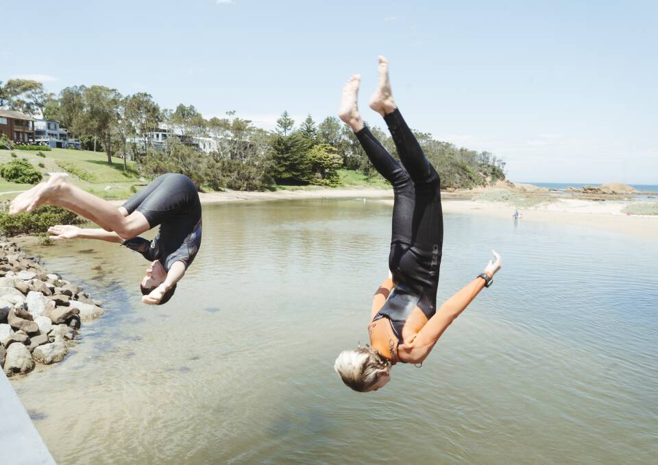 Children holidaying at Broulee last week perfect their jumps off the bridge over Candlagan Creek. But the Sydney COVID-19 outbreak has caused uncertainty for summer plans as south coast businesses record numerous cancellations. Picture: Dion Georgopoulos