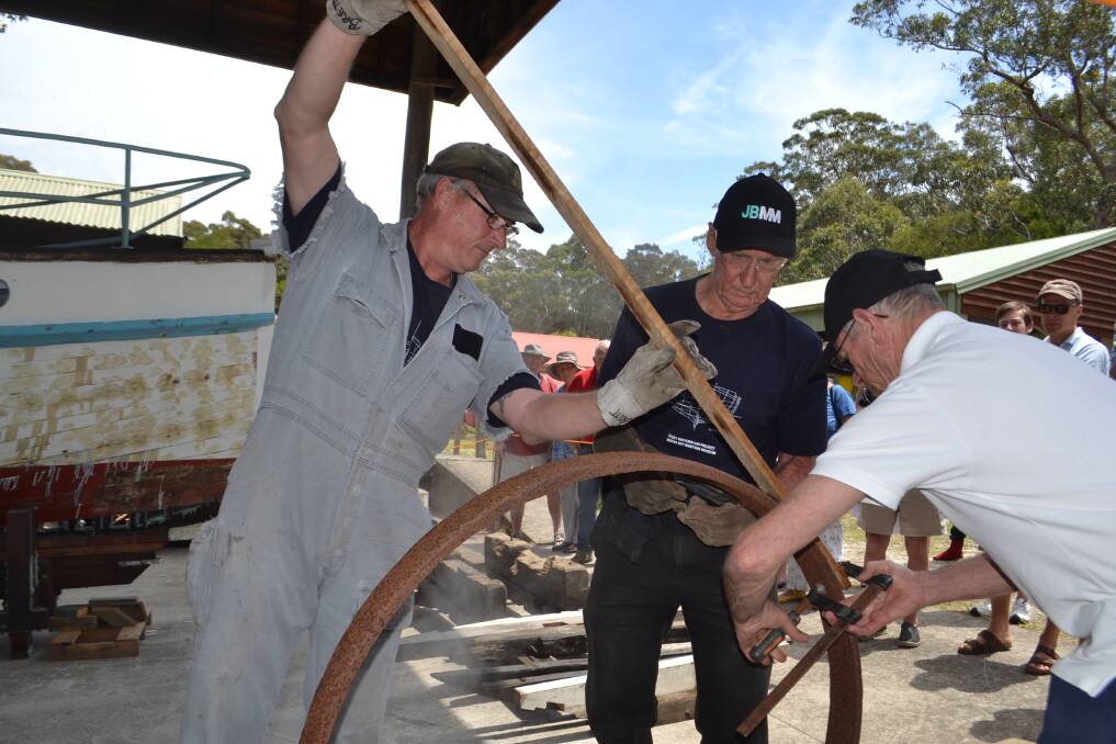 Ship restorers bending a heated piece of wood to a semi-circular shape in their wooden ship building workshop at the museum's wooden boat festival in November. Picture: Rebecca Fist