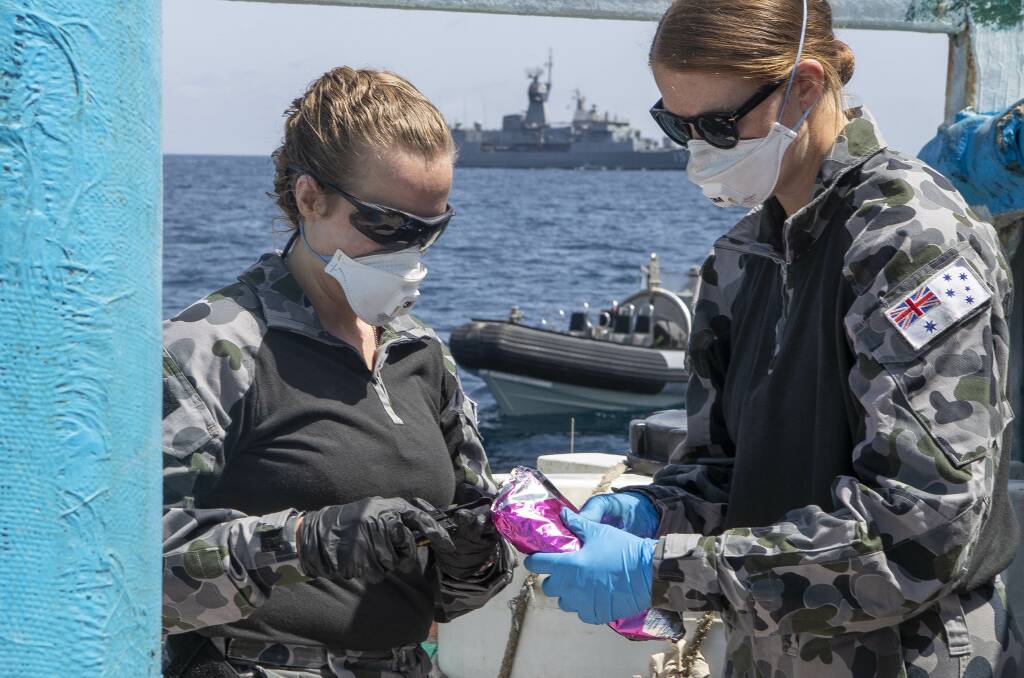 Lieutenant Maree Altham (left) and Lieutenant Shannen Rowe from HMAS Toowoomba conduct tests on a parcel discovered after boarding and searching a dhow in the Gulf of Aden on March 19. Photo: Richard Cordell
