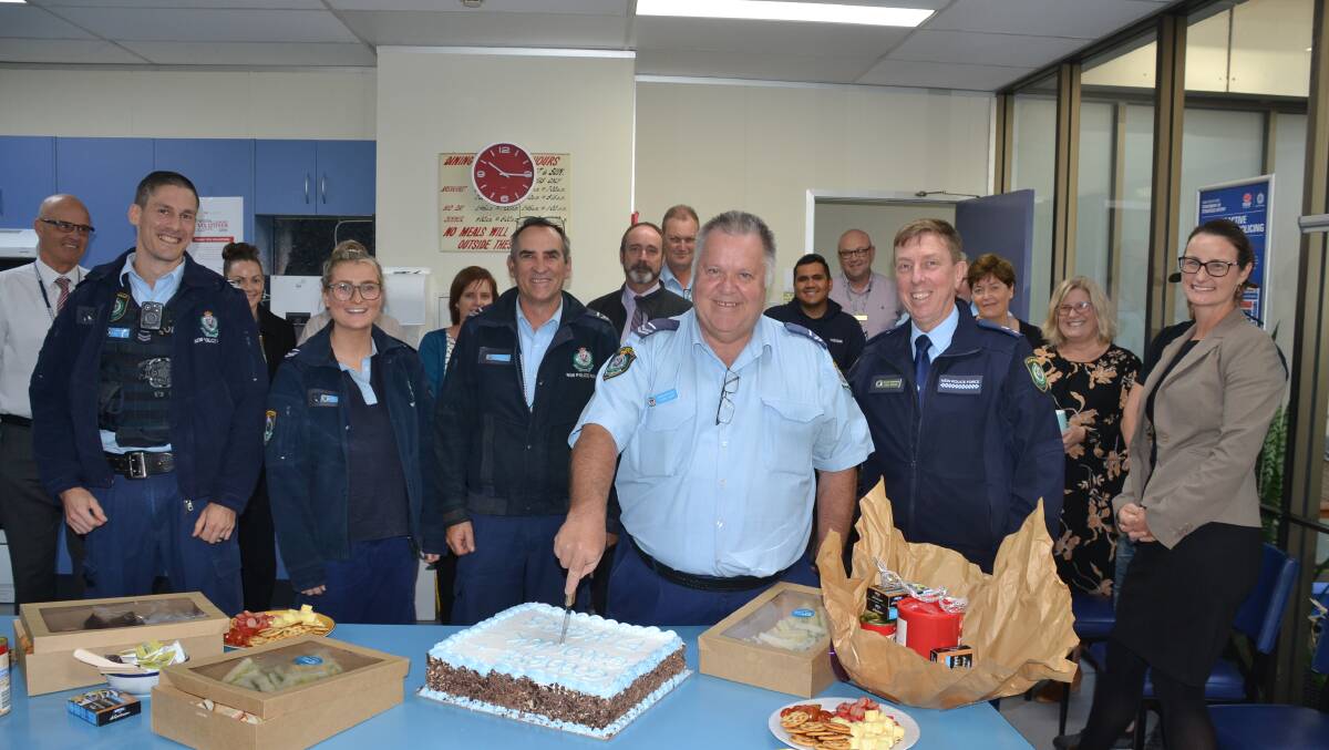 FAREWELL: Senior Constable Anthony Fingers Jory cuts his farewell cake with colleagues.