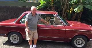 ON THE ROAD: Another of his cars, his much-loved BMW 2002 Tii, of course with Duke in the front seat. Photo supplied