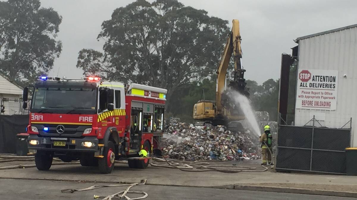 BLAZE: Fire and Rescue NSW crews wet down rubbish as its removed by excavator from an early morning fire at the Shoalhaven Recycling Centre in Bomaderry.
