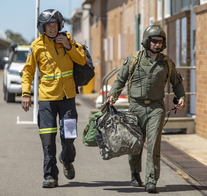 Rural Fire Service volunteer Jeff Hodder (left) and Lieutenant Commander Michael Cairncross, prepare to leave Royal Australian Air Force Base Williamtown, Newcastle, to support the firefighting efforts in NSW. Photo: Leo Baumgartner