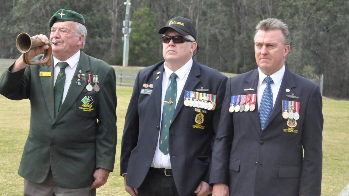 Shoalhaven Digger Day vice-chairman Fred Campbell (centre) and chairman Rick Meehan show their respect as bugler Peter Williams plays the last post at this year's event at Rugby Park. Photo: Damian McGill