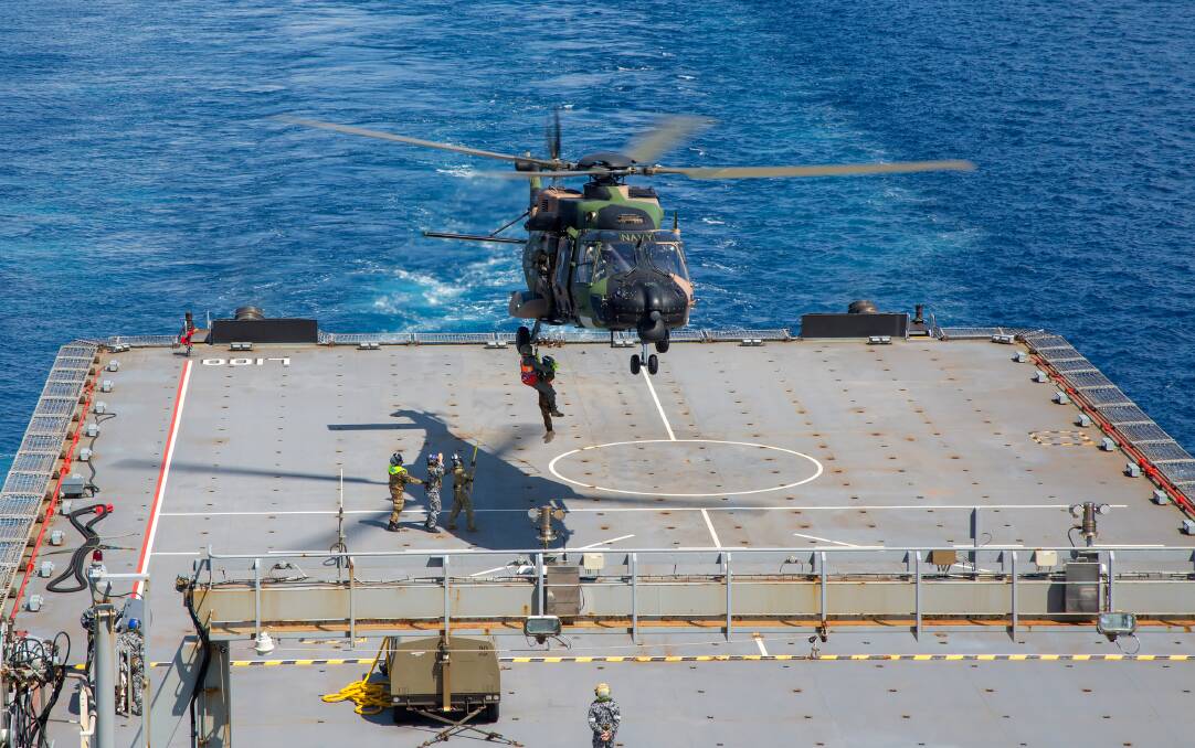 A MRH-90 Multi Role Helicopter conducts winching drills by winching Leading Seaman Aircrew man Brendan Menz and a member of the Papua New Guinea Defence Force Maritime Element down to the deck of HMAS Choules during a deployment to the South West Pacific region. Photo: Justin Brown