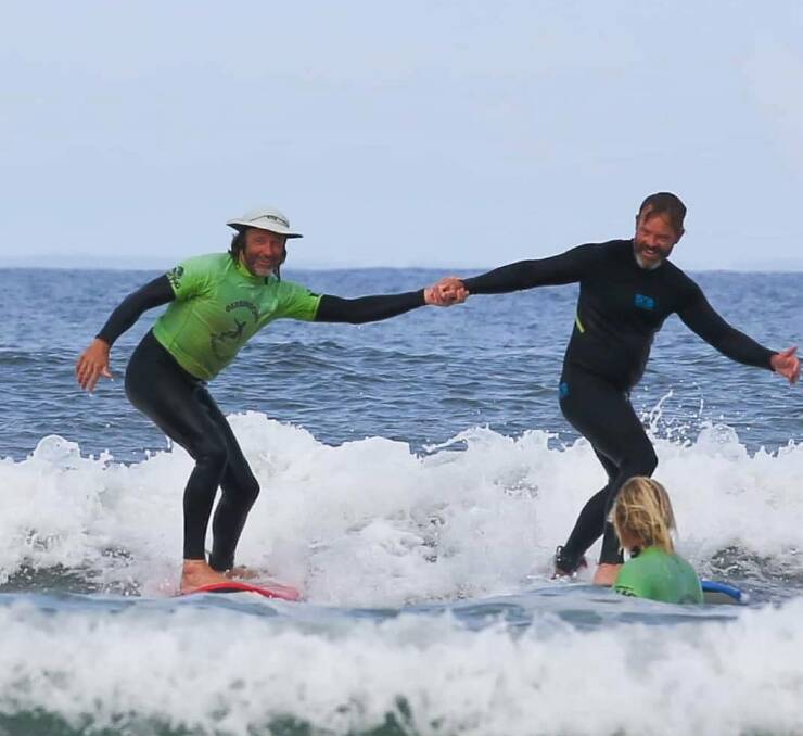 GREAT PROGRAM: Veteran Surf Project coordinator Rusty Moran (left) and a veteran hit the waves together at at Seven Mile Beach. Photo: Levi Cahill Photography