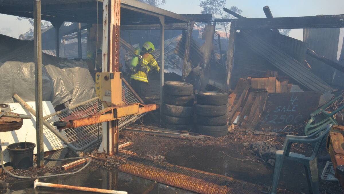 Fire and Rescue NSW crews blacken out the shed lost in the Bomaderry fire. Photo: Damian McGill