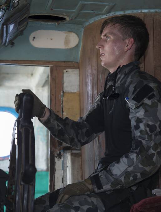 Able Seaman Electronic Warfare Justin Springer mans the helm of a dhow after HMAS Ballarat's boarding party conducted a search in the Arabian Sea which resulted in the seizure of hashish and illegals narcotics. Photo: Bradley Darvill
