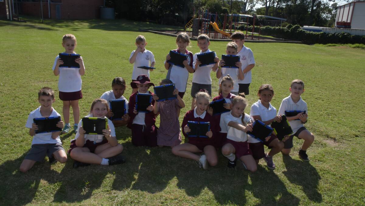 Nowra Public students use their iPads to record a visit to the school from helicopter from HMAS Albatross during Anzac Day activities.