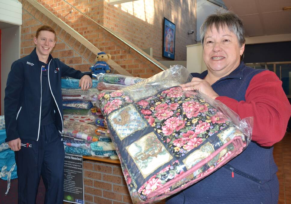 HELPING HAND: Quilter Dianne Croft hands over her donation of 50 quilts to Shoalhaven PCYC activities officer Jay Allen.