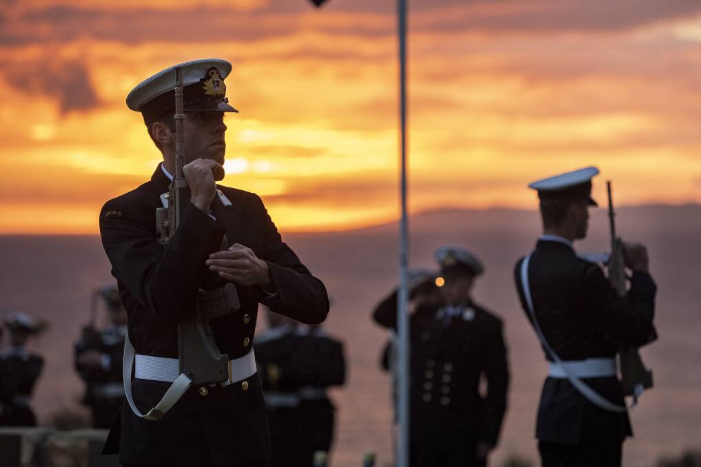 RESPECT: The catafalque party and guard comprising of members of the New Entry Officer Cadet class 64 present arms as the sun rises, during the Anzac Day dawn service at HMAS Creswell, Jervis Bay. Photo: Cameron Martin