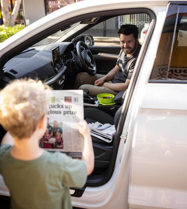 LOOK DAD: Louie Tagg shows his father Shane his front page appearance on the South Coast Register. Image: Rachael Tagg Photography
