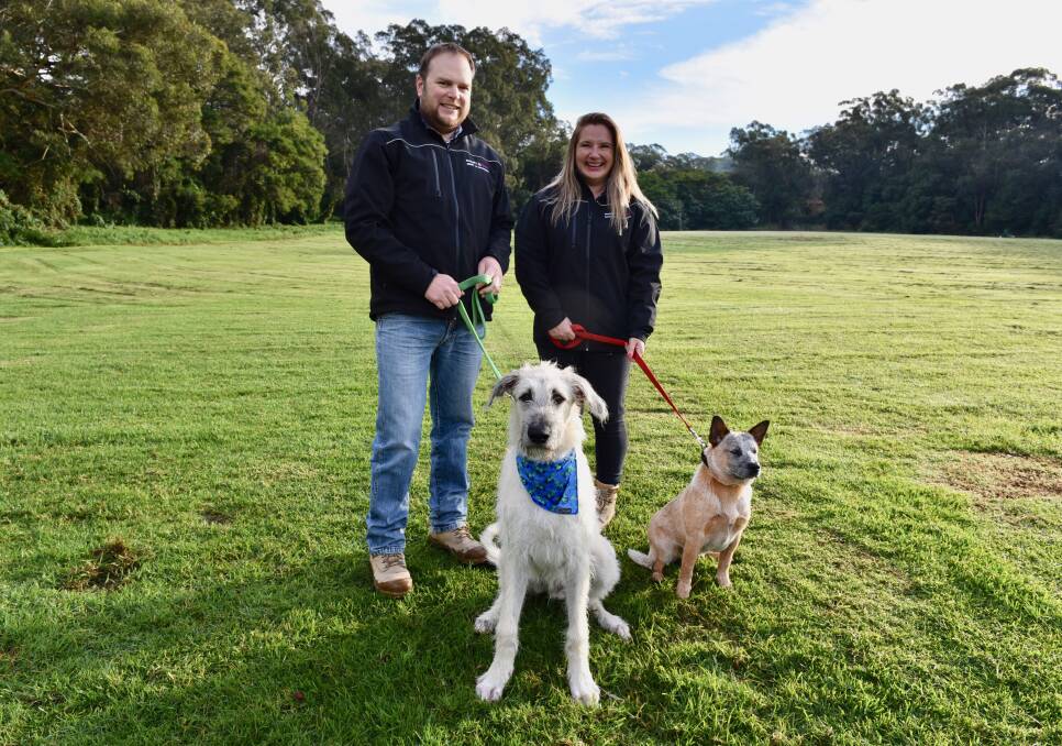 CONTRIBUTION: Downer Semour Whyte project manager Lewis Browne with Havoc, a wolfhound puppy and community relations advisor Renee Ciapponi with Ruby the cattle dog on the site of Bomaderry's proposed dog park, Thurgate Oval.