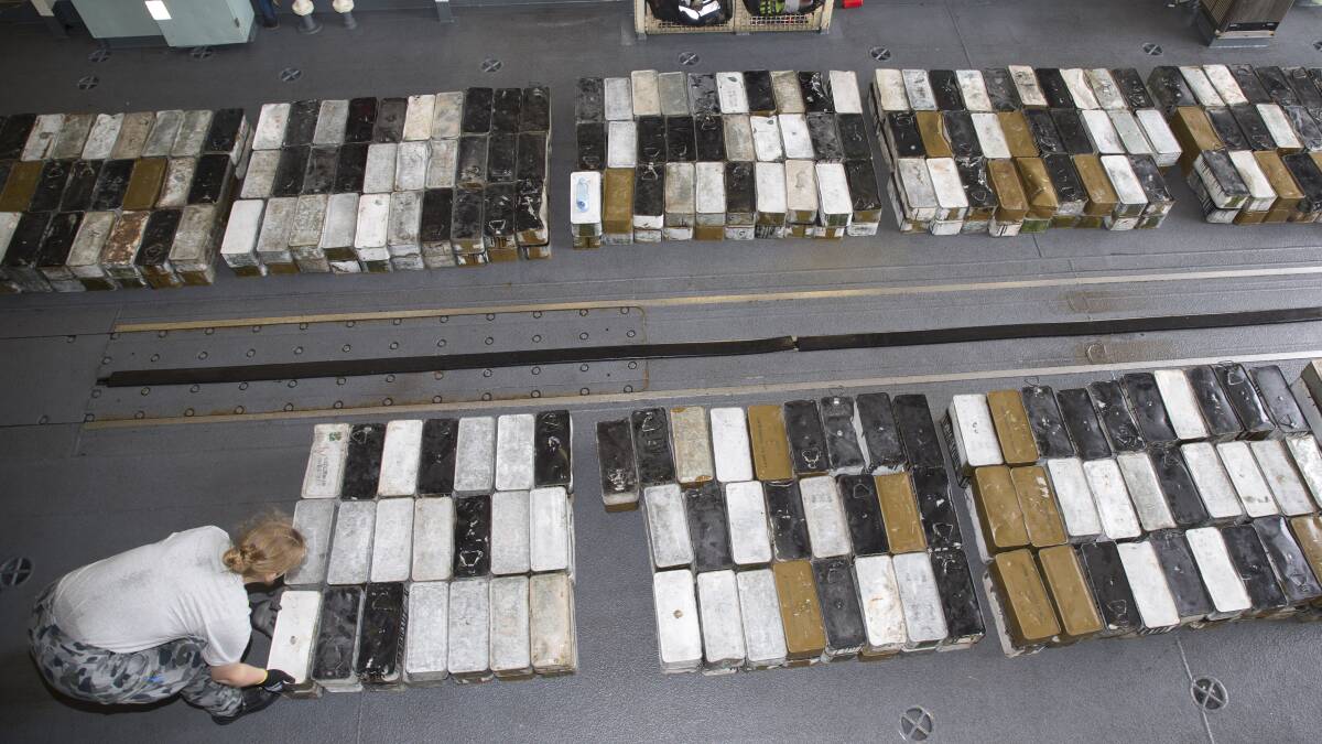 Lieutenant Megan Ryan stacks boxes ammunition seized during a boarding in HMAS Ballarat's hangar. Photo: Bradley Darvill