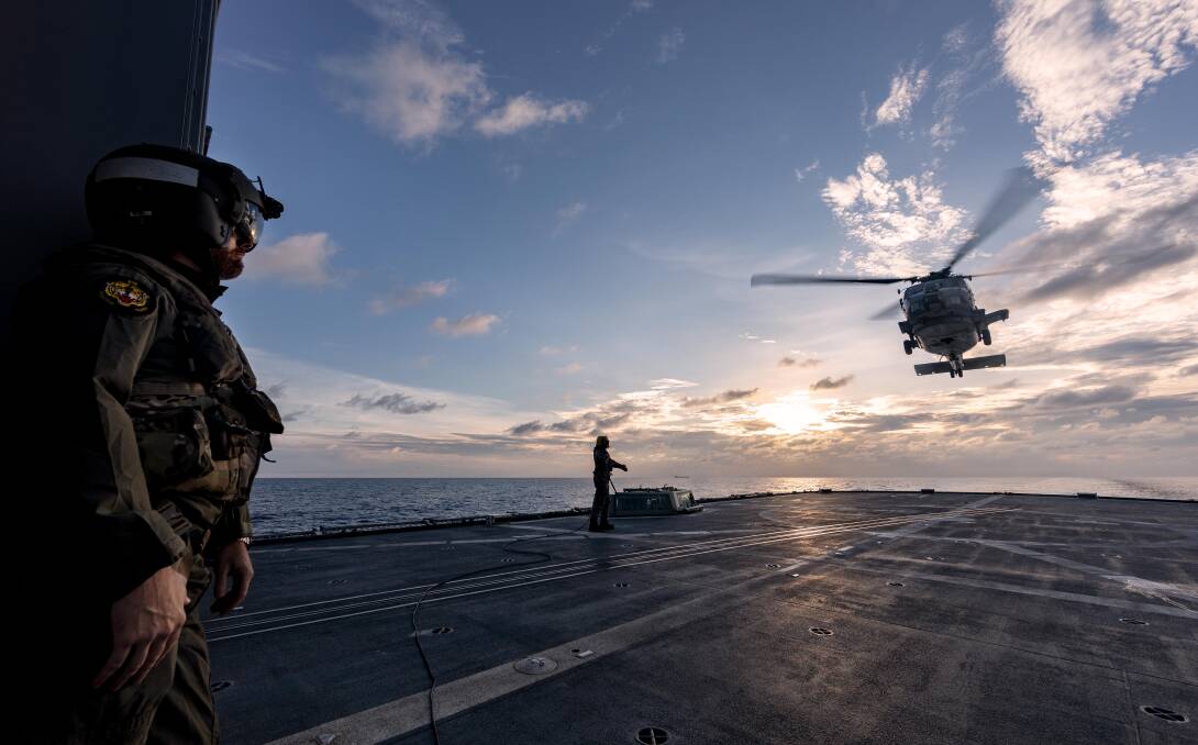 DEPARTURE: Lieutenant Commander Matthew Schroder (left) observes the departure of a US Navy MH-60R helicopter from HMAS Ballarat's flight deck during Exercise Malabar 2020. Photo: Shane Cameron