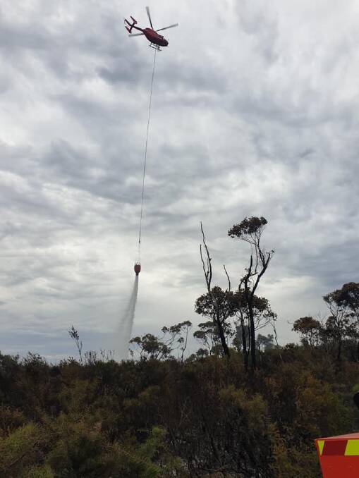 ON THE JOB: A helicopter waterbombing on the Booderee National Park fire. Image: Andrew Catt Crossroads RFS