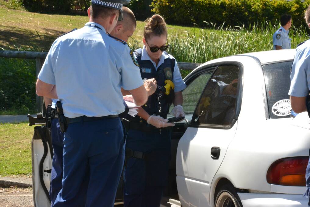 AFTERMATH: Police search the white Subaru Impreza after Tuesday's chase came to an abrupt halt in Kalander Street, Nowra, when the car crashed.

