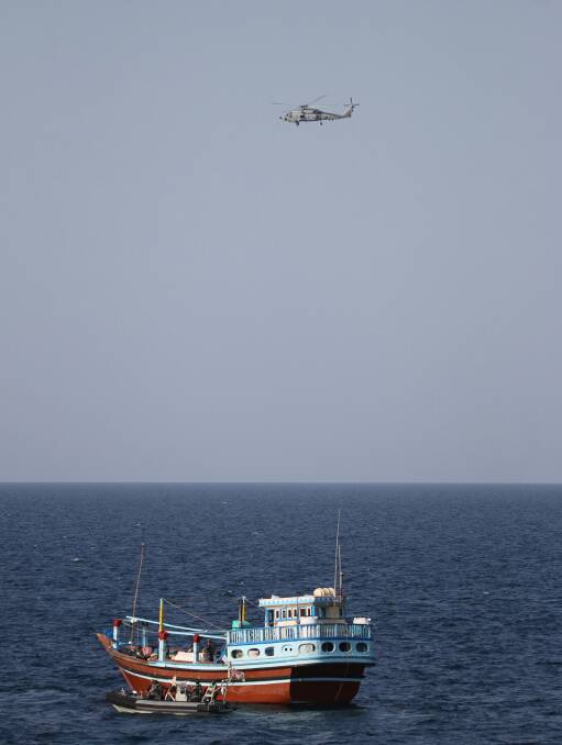 HMAS Ballarat's MH-60R Seahawk helicopter provides over watch as the ship's boarding party conducts a flag verification boarding on a suspicious dhow in the Arabian Sea. Photo: Bradley Darvill
