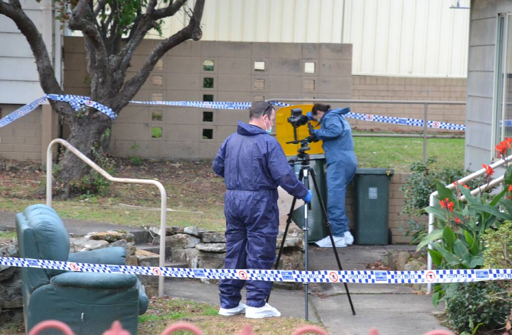 Forensic officers examine the area around the Nowra unit where the man was found.
