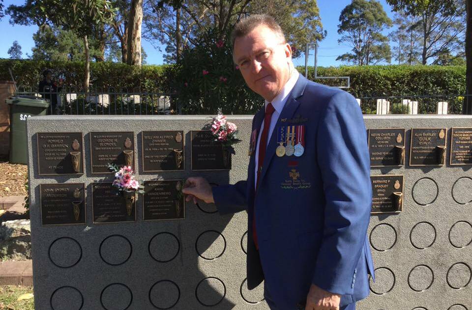Keith Payne VC Veterans Benefit Group chairman Rick Meehan lays some rosemary for his late former mate Kane Vandenberg in the naval cemetery section.
