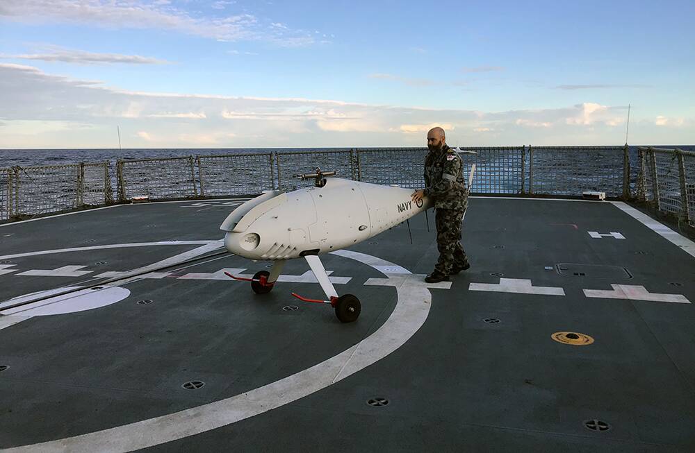 TESTING: 822X Squadron deputy engineer Lieutenant Gareth Forbes recovers the S-100 Camcopter on HMAS Ballarats flight deck. Photos: Michael Mulquiney, Markus Winhofer
