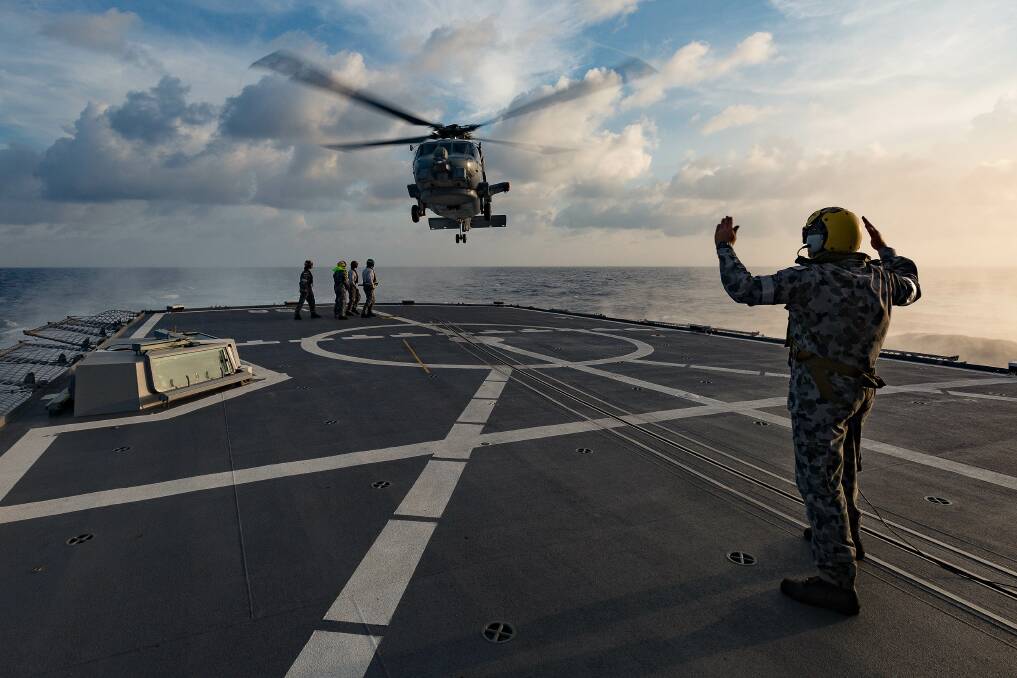 MANOEUVRE: HMAS Toowoomba's MH-60R helicopter prepares to conduct a personnel transfer at sea. Photo: Steven Thompson
