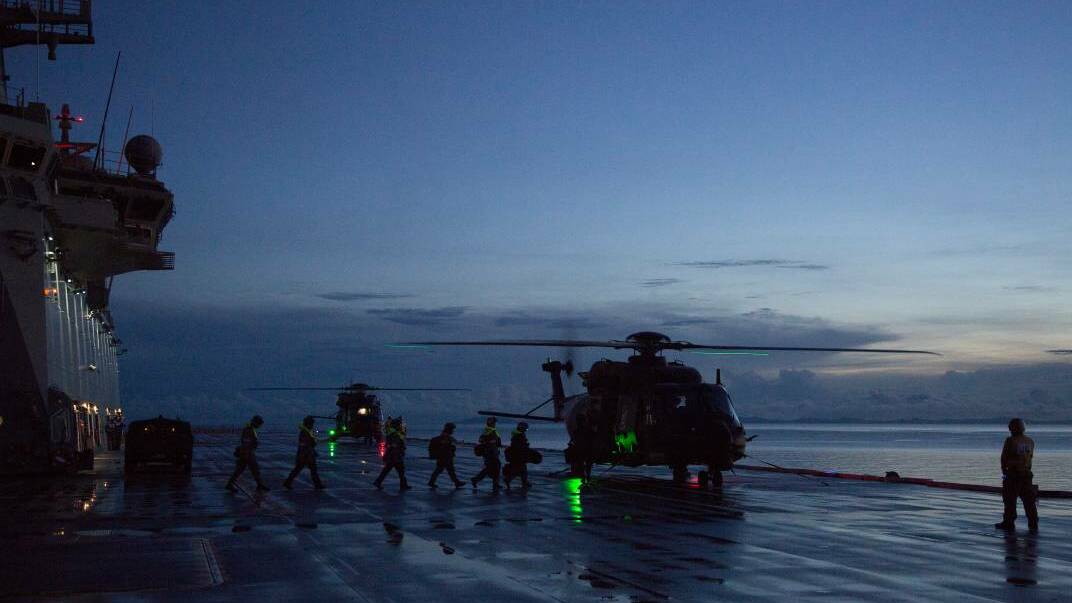 EMERGENCY: The medical team and Solomon Island Police Force personnel walk to a waiting MRH-90 helicopter on HMAS Adelaide supporting a medical evacuation from an island near Honiara, Solomon Islands. Photo: Damian Pawlenko
