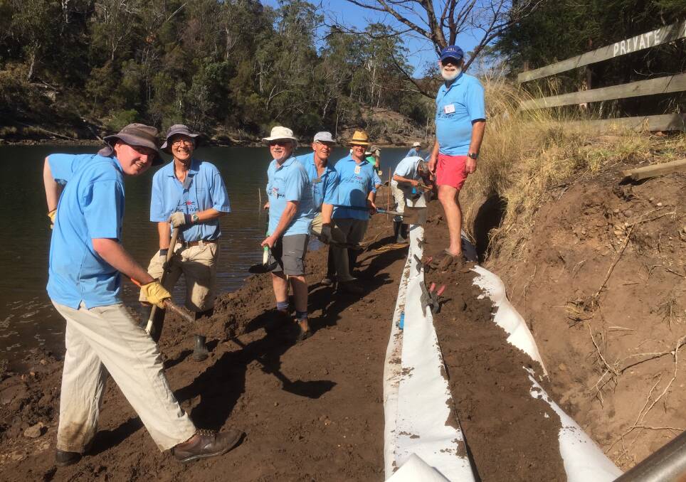 Shoalhaven Riverwatch volunteers Len White, Raymond Martin, John Miskelly, Peter Jirgens, Peter Hanson and Ed Tap busily constructing the sand sausage at Yowaka River, Pambula
