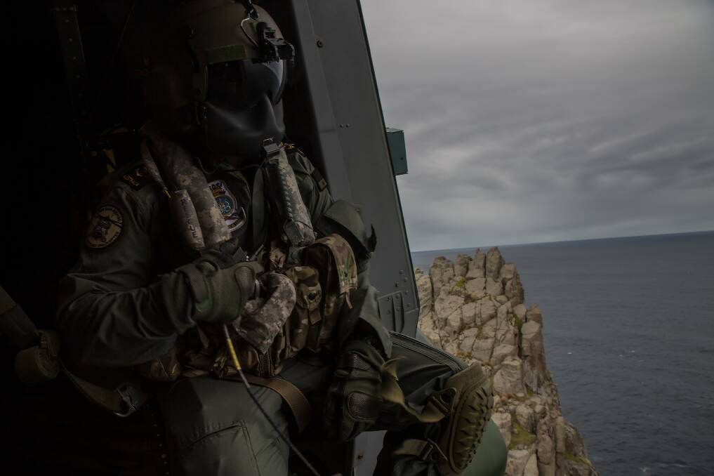 Leading Seaman Aircrewman Brendan Menz gazes out the door of HMAS Choules's embarked MRH-90 Multi Role Helicopter. Photo: Justin Brown