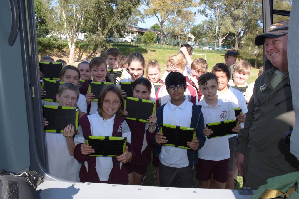 Nowra Public students use iPads to record a visit from a HMAS Albatross helicopter to the school during Anzac Day activities. 