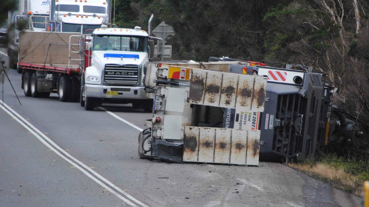 HORROR CRASH: The semi-trailer low-loader, carrying road working machinery, came to rest on its side after a fatal accident on the Princes Highway at Bewong. Photo: Damian McGill