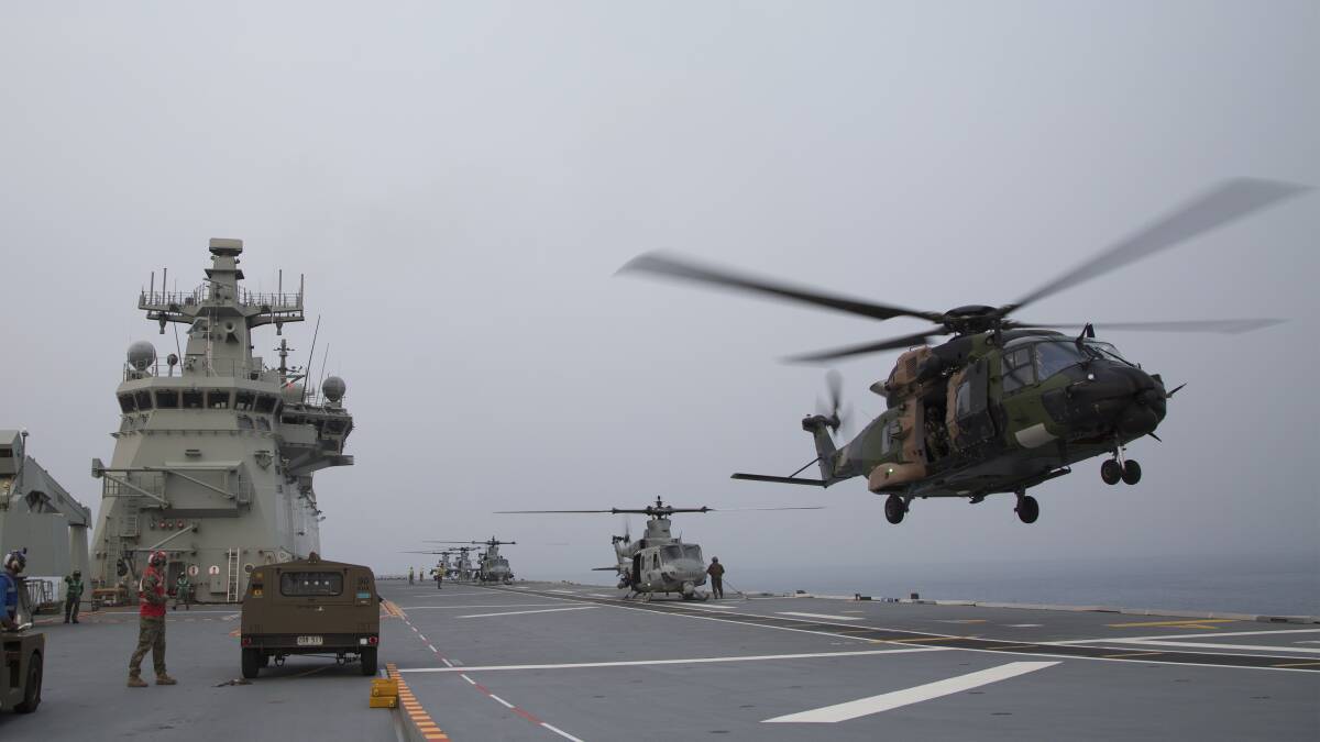 A Royal Australian Navy MRH-90 helicopter from 808 Squadron takes off as four United States Marine Corps helicopters line HMAS Adelaide's flight deck during a multi-spot exercise. Photo: Tara Byrne.