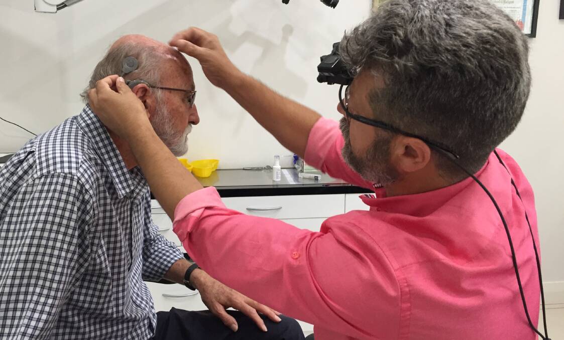GAME CHANGER: Dr Ekrem Serefli examines Nowra man Ian "Tiny" Warren's cochlear implant, which he has decided as a "game changer" that has "returned his quality of life".